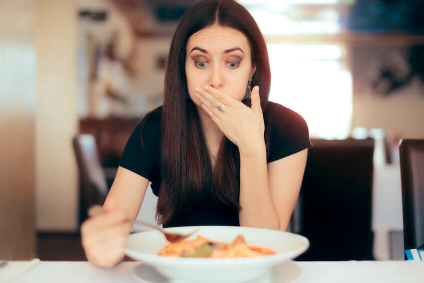 Die Frau fühlt sich beim Essen im einem Restaurant krank.