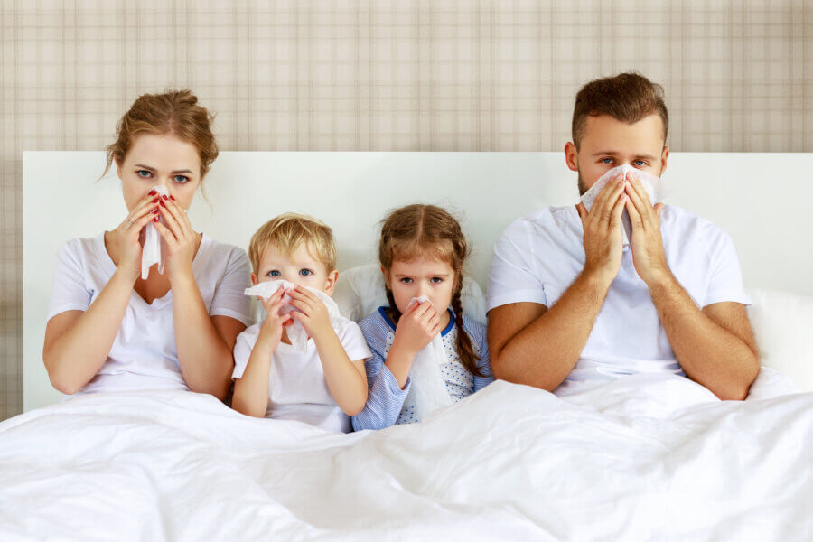 Erkältung und Viruserkrankungen. Familie mit laufende Nase und Fieber im Bett zu Hause