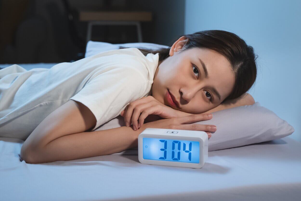 Mit geöffneten Augen auf dem Bett liegen eine Frau mit Schlaflosigkeit.