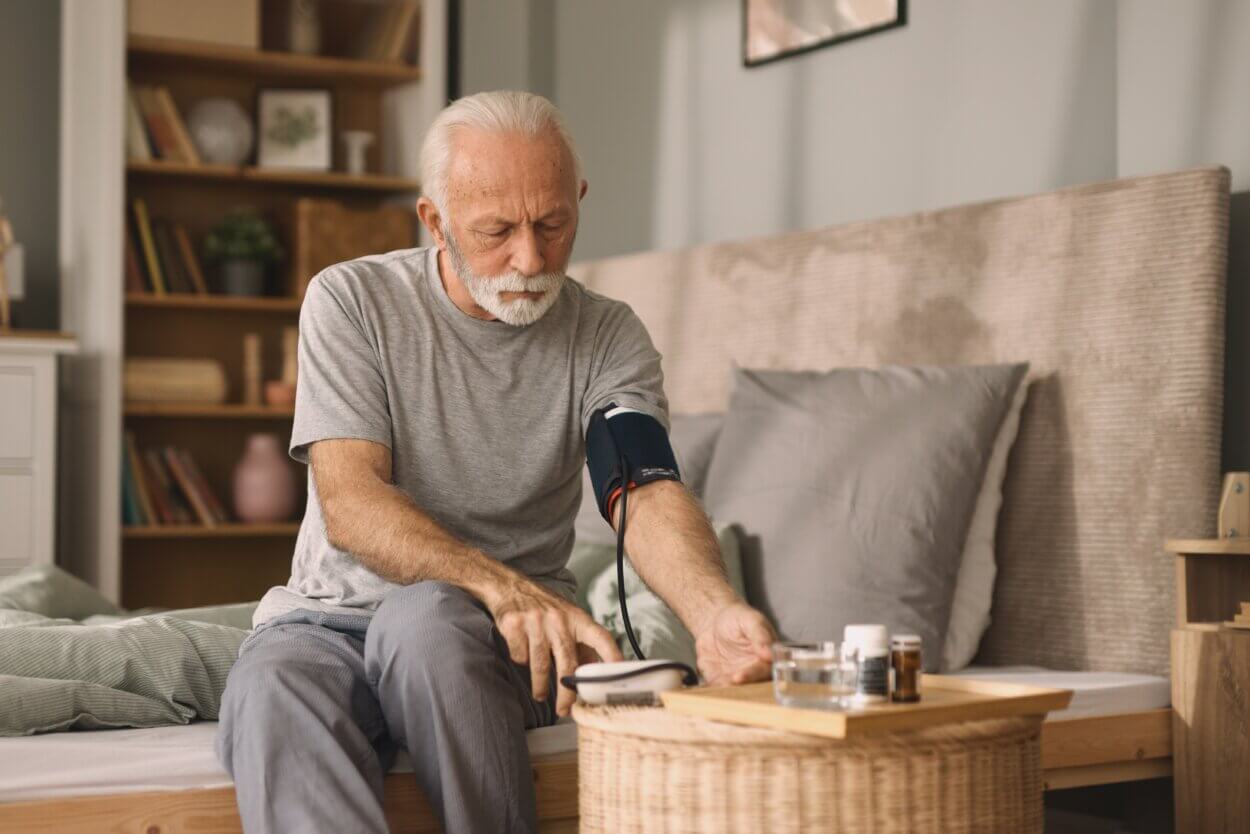 Älterer Mann, der den Blutdruck im Bett misst